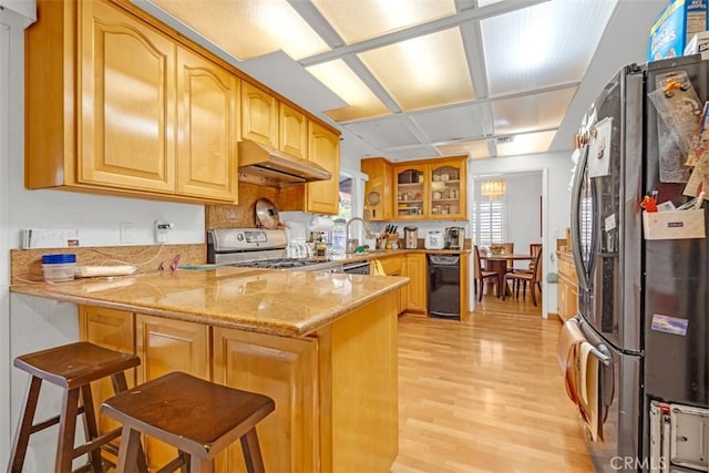 kitchen featuring kitchen peninsula, light stone counters, a breakfast bar, and stainless steel appliances