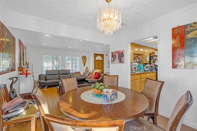 dining space featuring ornamental molding, a chandelier, and light hardwood / wood-style floors