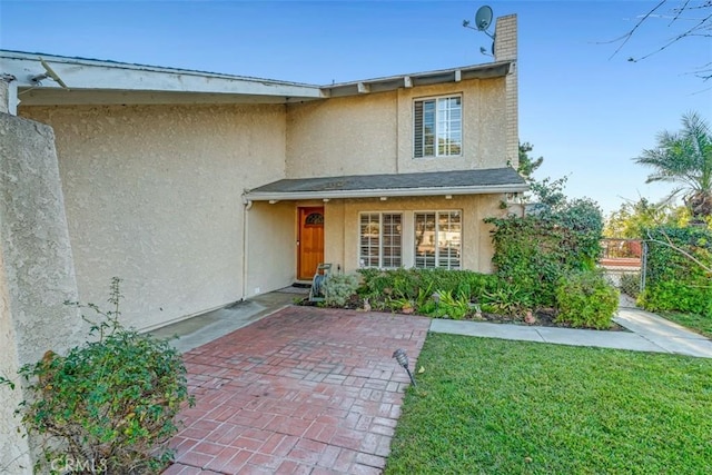 doorway to property featuring a lawn and a patio