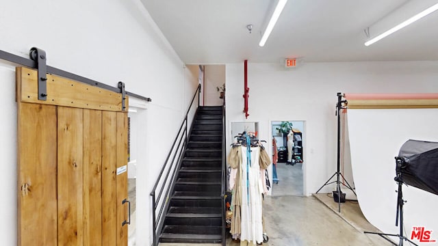 staircase with a barn door and concrete flooring