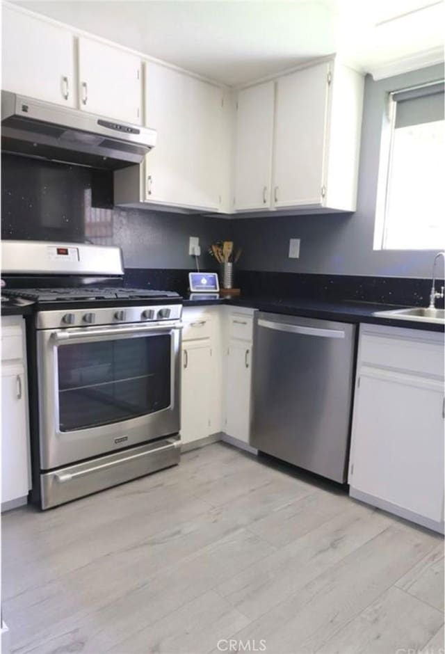 kitchen with white cabinets, appliances with stainless steel finishes, light hardwood / wood-style flooring, and sink