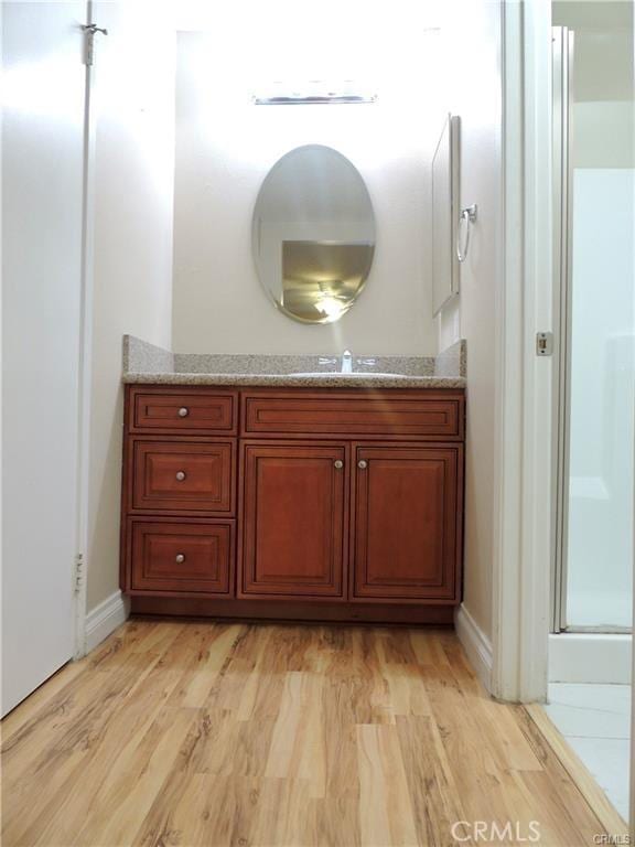 bathroom with a shower with shower door, wood-type flooring, and vanity