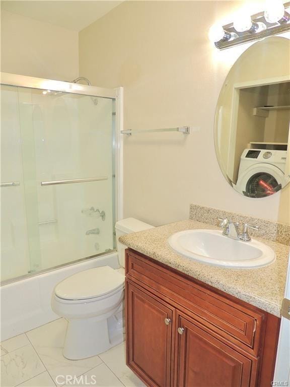 full bathroom featuring vanity, combined bath / shower with glass door, toilet, and washer / clothes dryer