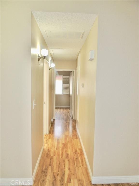 hall with light hardwood / wood-style floors and a textured ceiling