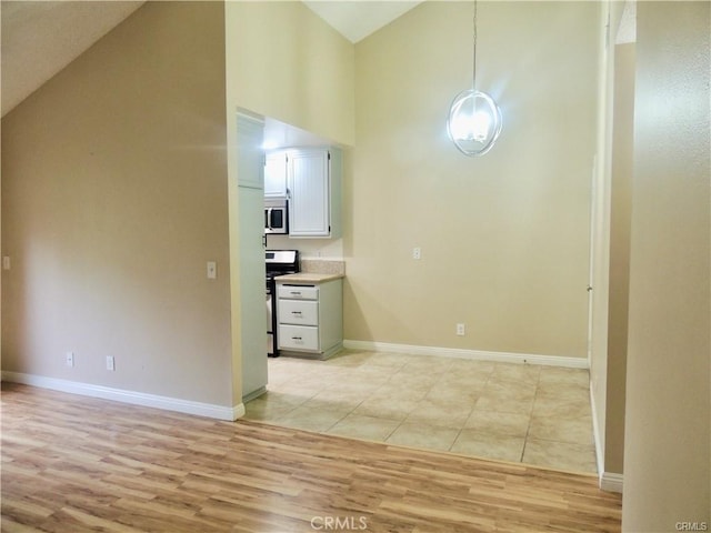 kitchen with light hardwood / wood-style floors, high vaulted ceiling, and stainless steel appliances