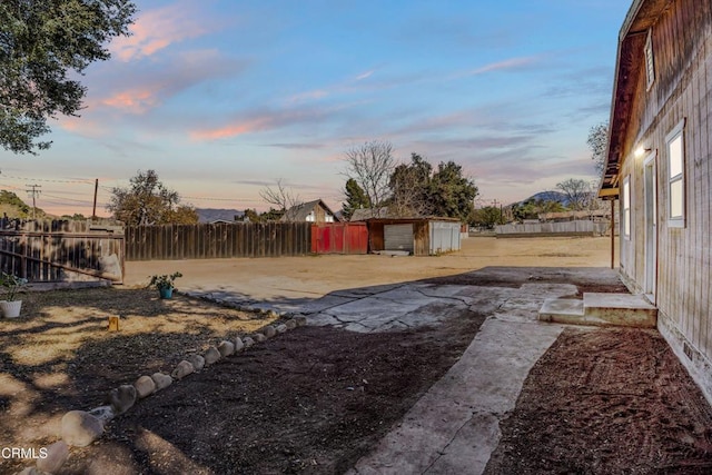 yard at dusk with a patio and a storage unit