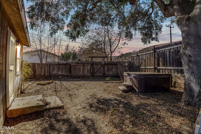 yard at dusk featuring a hot tub