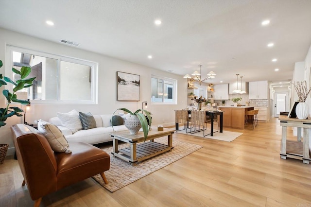 living room featuring light wood-type flooring, a wealth of natural light, and a chandelier