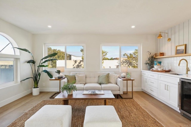 living room with light hardwood / wood-style floors, wine cooler, and indoor wet bar