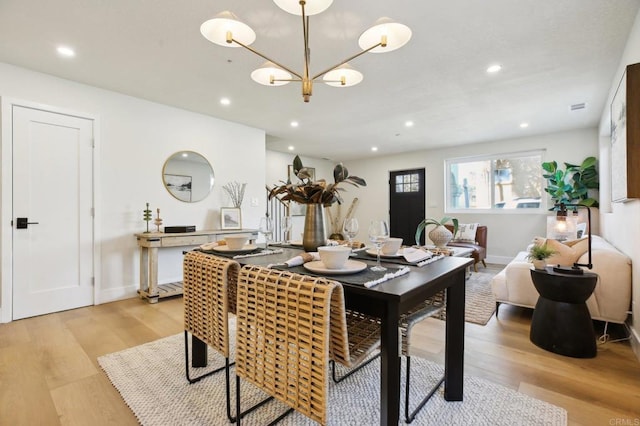 dining space with light hardwood / wood-style flooring and a chandelier