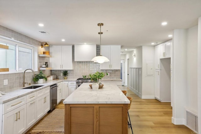 kitchen with a center island, sink, white cabinetry, and hanging light fixtures