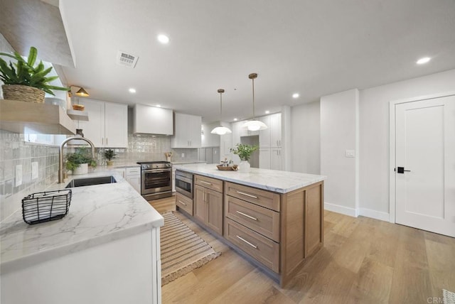 kitchen featuring pendant lighting, a center island, white cabinets, sink, and appliances with stainless steel finishes