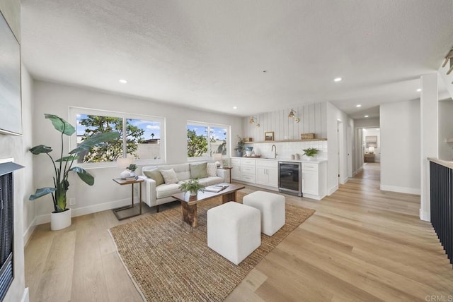 living room with light hardwood / wood-style floors, sink, and wine cooler