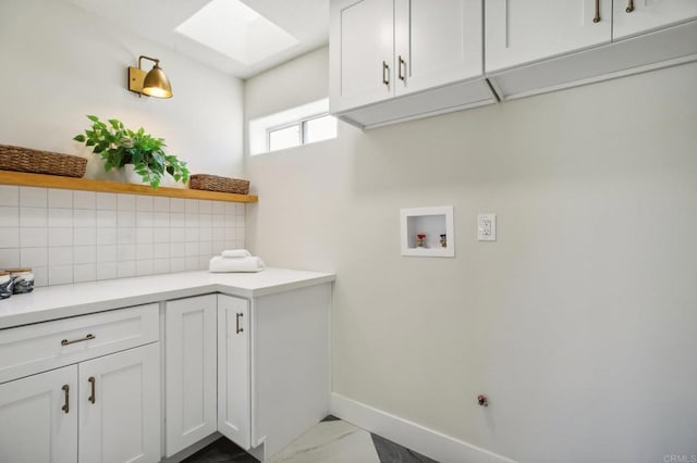 clothes washing area featuring a skylight, hookup for a washing machine, and cabinets