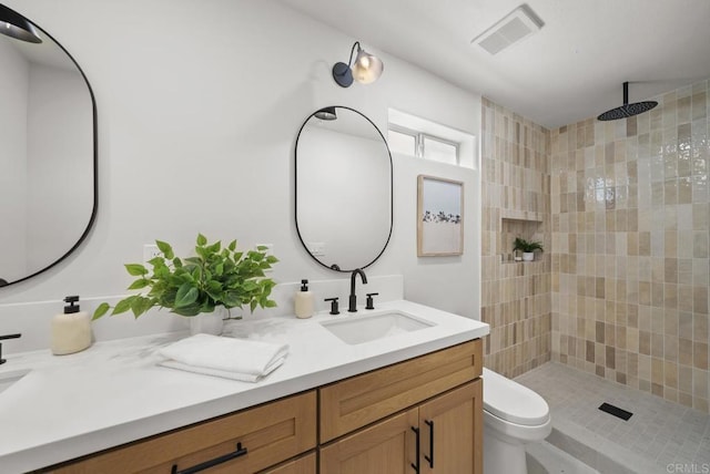 bathroom with toilet, vanity, and tiled shower