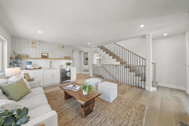 living room with wine cooler, wet bar, and light wood-type flooring