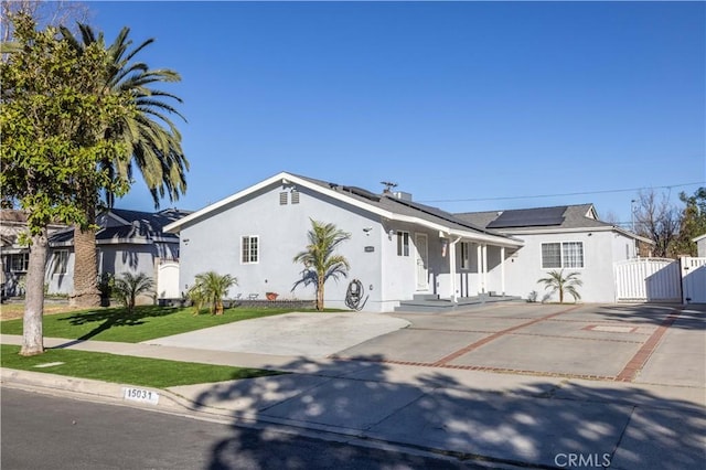 ranch-style house featuring solar panels and a front lawn