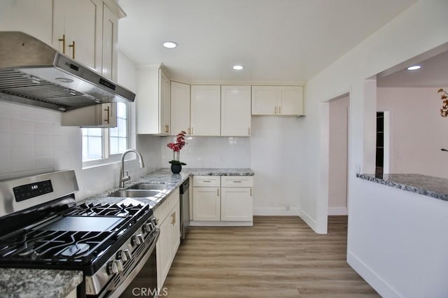 kitchen featuring stainless steel appliances, white cabinetry, sink, and light stone countertops