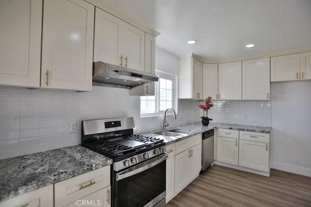 kitchen featuring light stone countertops, stainless steel appliances, decorative backsplash, light wood-type flooring, and sink