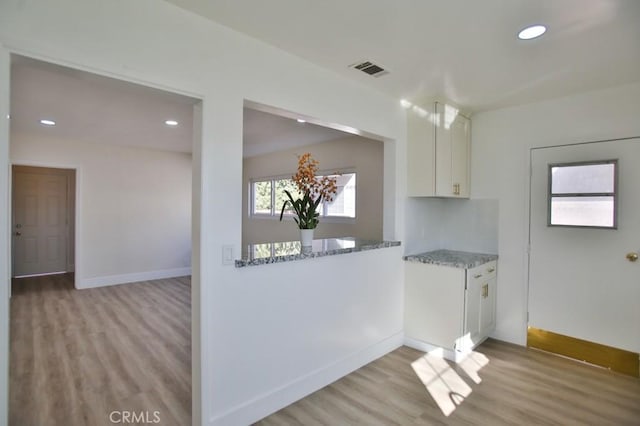 kitchen with white cabinets, stone countertops, and light hardwood / wood-style floors