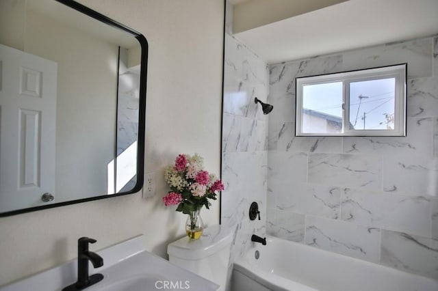 full bathroom with sink, tiled shower / bath combo, and toilet