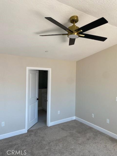 empty room featuring ceiling fan, a textured ceiling, and carpet flooring