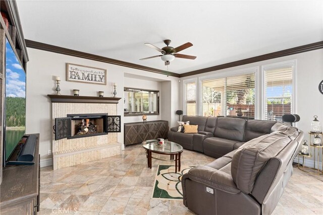 living room with a tile fireplace, ceiling fan, and ornamental molding