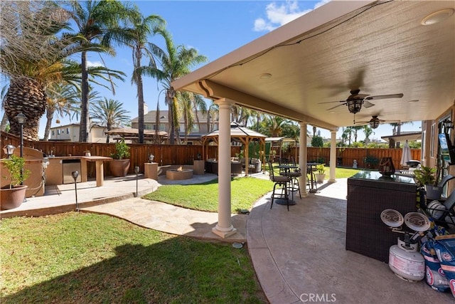 view of yard with an outdoor living space with a fire pit, ceiling fan, and a patio