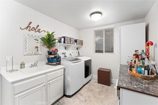 clothes washing area featuring sink, cabinets, and washing machine and clothes dryer