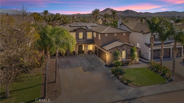 view of front of home with a yard, solar panels, a garage, and a mountain view