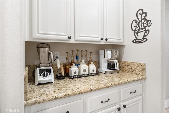 bar featuring white cabinets and light stone countertops