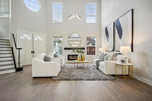 living room with a towering ceiling and wood-type flooring