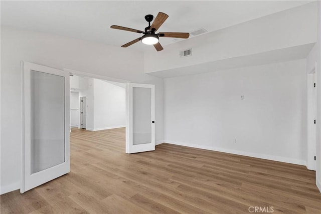 empty room with ceiling fan, light hardwood / wood-style flooring, and french doors