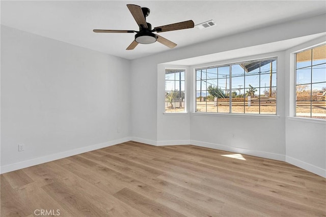 empty room featuring ceiling fan, light hardwood / wood-style flooring, and a healthy amount of sunlight