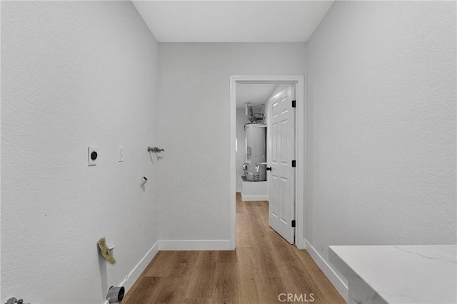 laundry room with light wood-type flooring, water heater, and hookup for an electric dryer