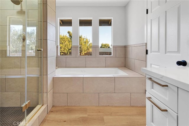 bathroom featuring plus walk in shower, wood-type flooring, and vanity