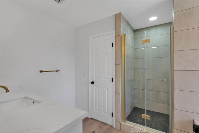 bathroom with a shower with door, hardwood / wood-style floors, and vanity