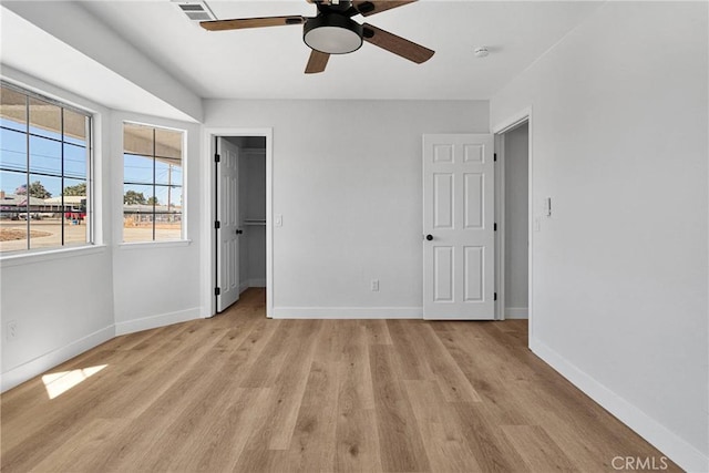 unfurnished bedroom featuring a closet, ceiling fan, light hardwood / wood-style floors, and a spacious closet