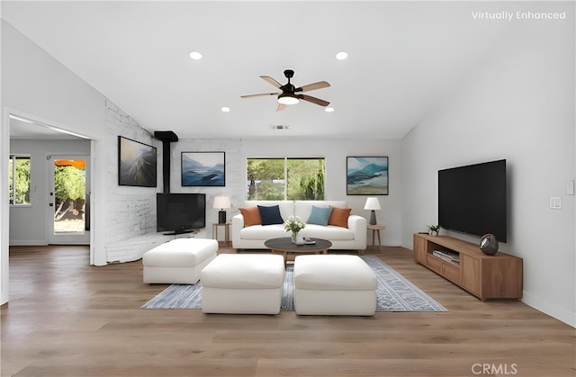 living room featuring light hardwood / wood-style floors, ceiling fan, and vaulted ceiling