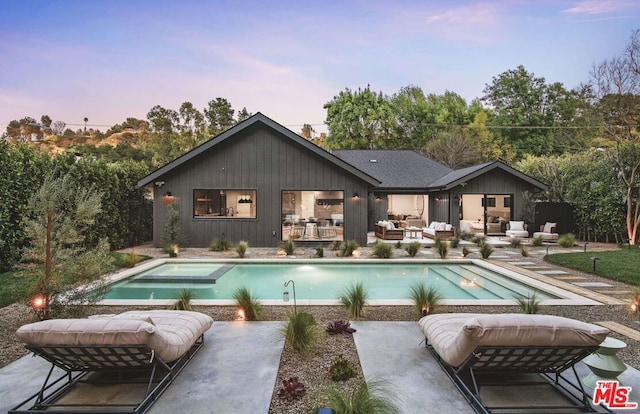 pool at dusk with a patio and an outdoor hangout area