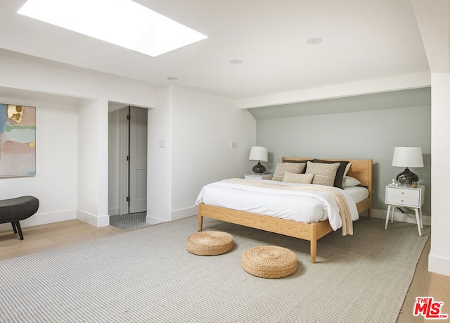 bedroom with a skylight and light wood-type flooring