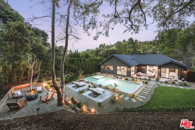 pool at dusk featuring outdoor lounge area and a patio