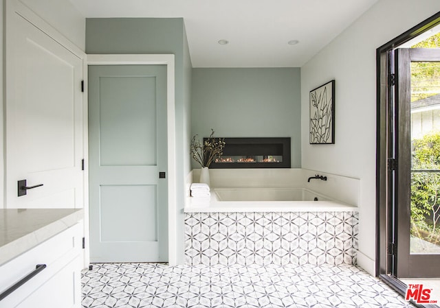 bathroom featuring tiled tub and vanity