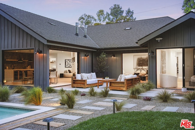 back house at dusk with an outdoor living space and a patio area