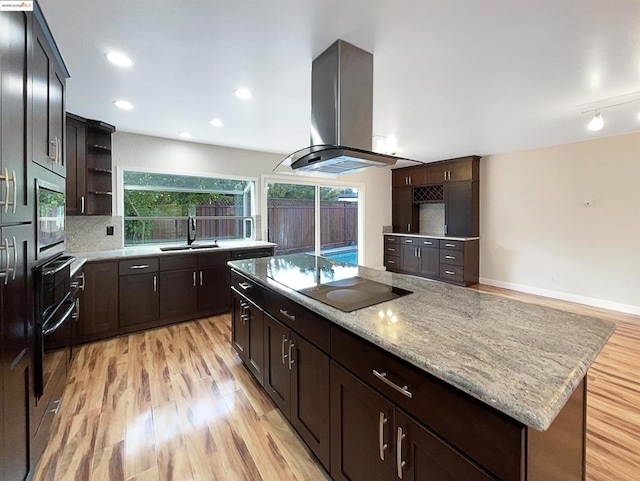 kitchen with a center island, sink, light hardwood / wood-style flooring, island exhaust hood, and black appliances