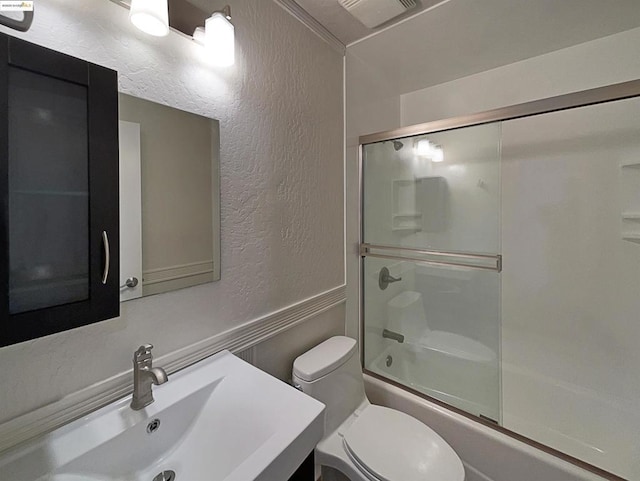 full bathroom with crown molding, sink, bath / shower combo with glass door, and toilet