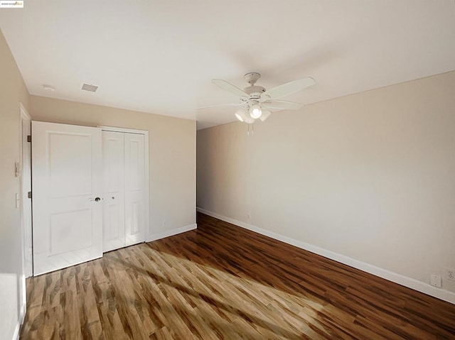 unfurnished bedroom featuring ceiling fan, a closet, and hardwood / wood-style flooring