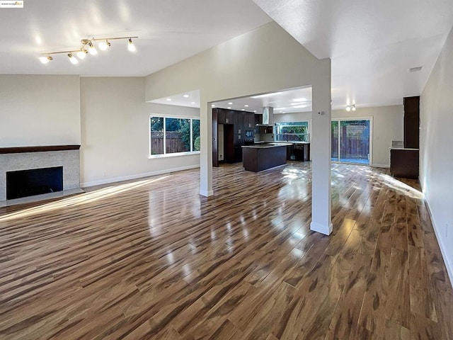 unfurnished living room featuring rail lighting and dark hardwood / wood-style floors