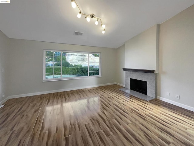 unfurnished living room with hardwood / wood-style floors, lofted ceiling, and track lighting