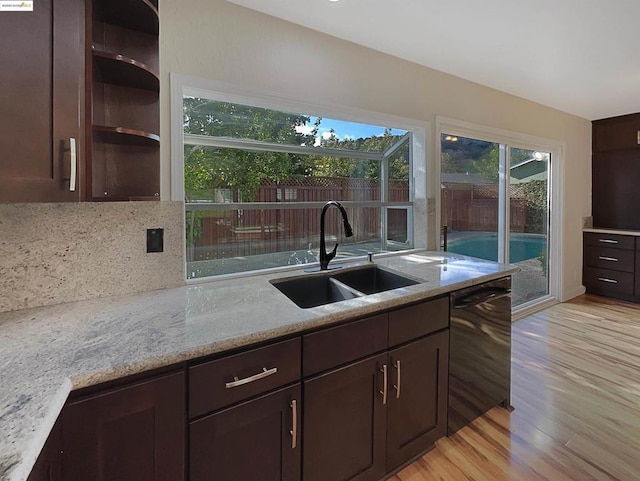 kitchen with light stone countertops, dark brown cabinets, dishwasher, and sink